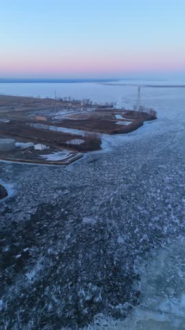 Aerial of Green Bay Wisconsin in Winter at Dusk.  Push drone shot of frozen river and Lake Michigan.
