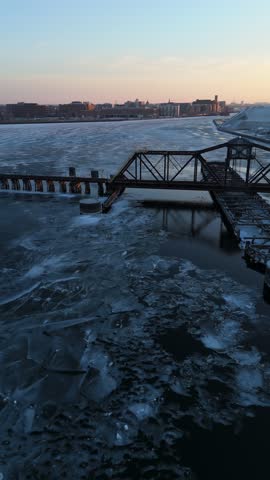 Aerial of the frozen Fox River and Green Bay Wisconsin at Dusk.  Stunning drone shot of old rail bridge.