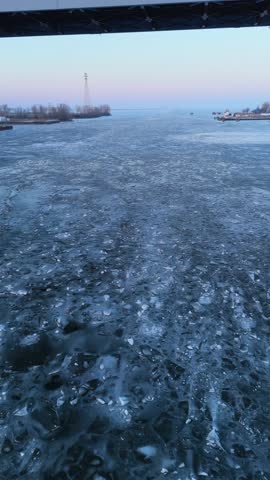 Aerial of the frozen Fox River and Green Bay Wisconsin at Dusk.  Slow Drone pull shot over river and view of Leo Frigo Bridge.