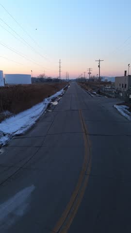 Aerial of the frozen Fox River and Green Bay Wisconsin at Dusk.  Low drone shot of road and industrial area.