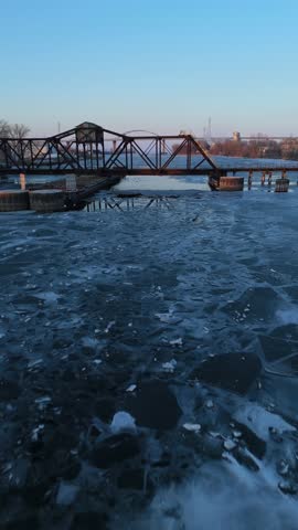 Aerial of the frozen Fox River and Green Bay Wisconsin at Dusk.  Approach shot of old Rail Bridge.