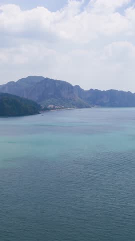 High angle wide shot of turquoise ocean water and limestone cliffs under a cloudy sky
