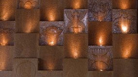Static medium shot of illuminated cultural stone carvings on a resort wall with warm lighting - Powered by Shutterstock - Get 15% off with code: PIKWIZARD15