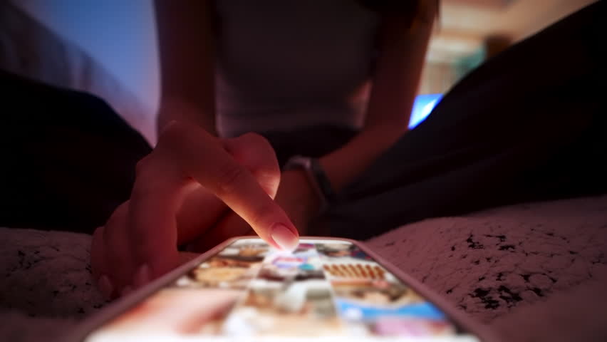 Unrecognizable Person Using Cellphone In Darkness Before Sleeping. Concept of Insomnia and Blue Light Affecting Eyes. Close Up View of One Woman Hand Holding Electronic Gadget While Lying on Home 4k