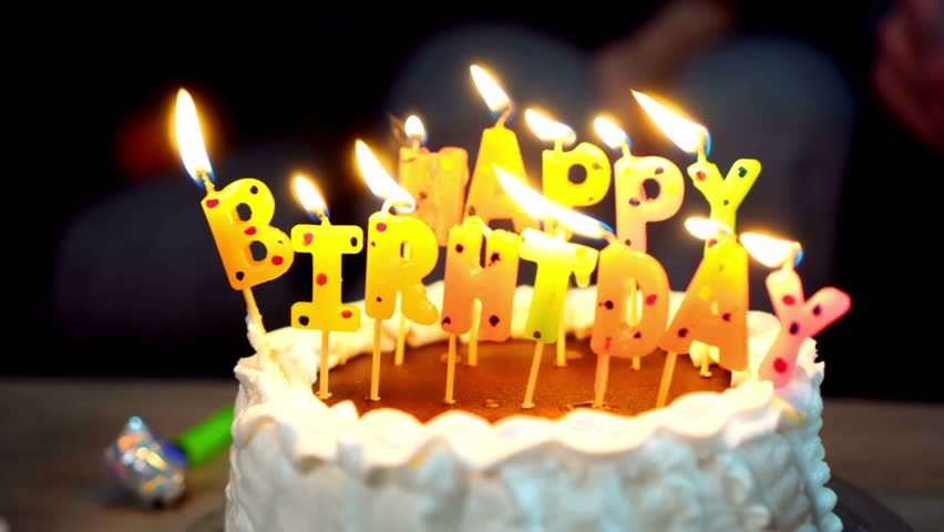 White birthday cake with Happy Birthday candles lit