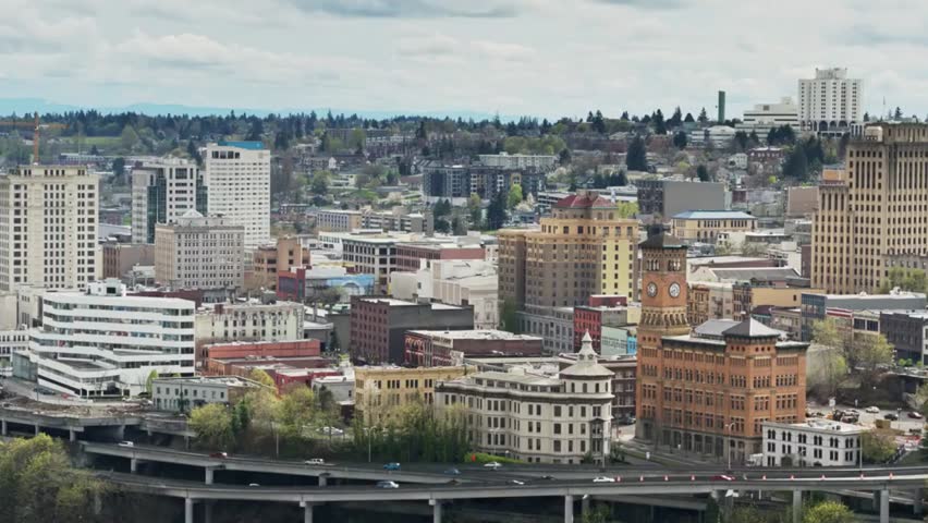 Daytime aerial view of Tacoma downtown, showing freeways, urban buildings, and the city layout under clear skies.