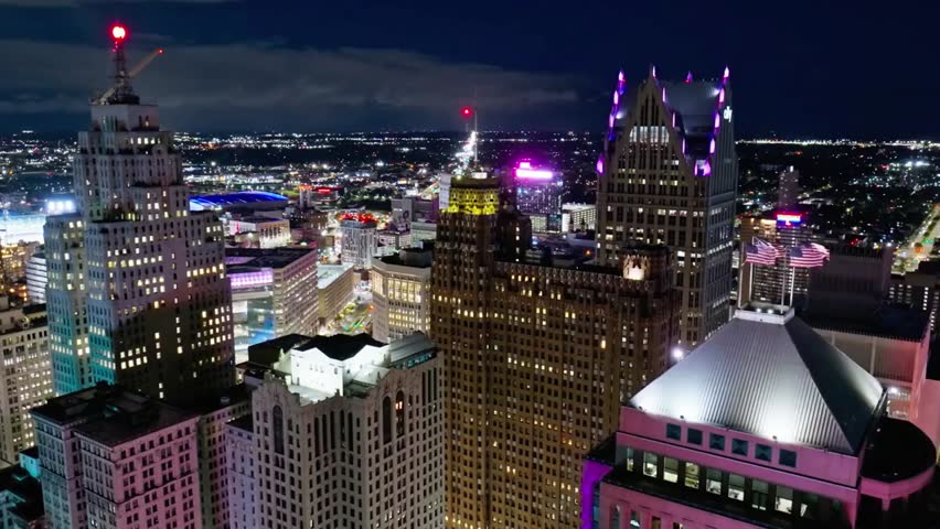 Nighttime aerial view of Detroit skyline with illuminated skyscrapers and sparkling city lights, capturing urban energy and architecture.