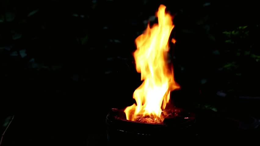 A burning flame casts a warm glow, illuminating the surrounding darkness at night, creating an intimate, cozy, and atmospheric scene.