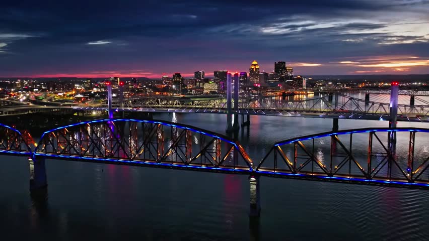 Aerial view of Louisville, Kentucky skyline at night with a bridge over the river, showcasing urban lights and scenic cityscape.