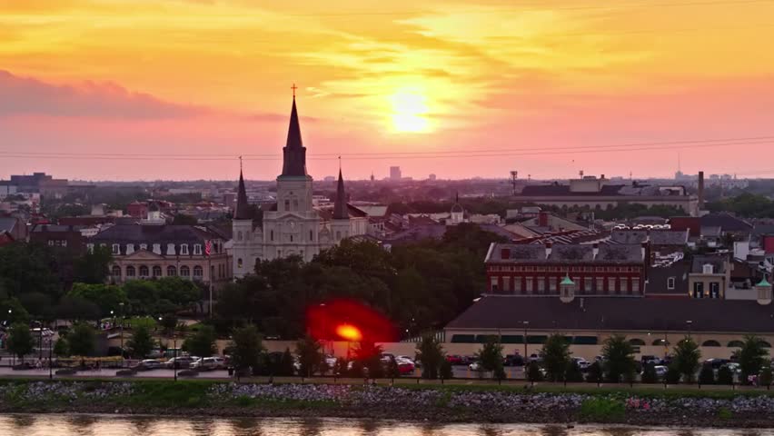 Sunset view of New Orleans French Quarter skyline with St. Louis Cathedral and the Mississippi River, highlighting historic architecture.
