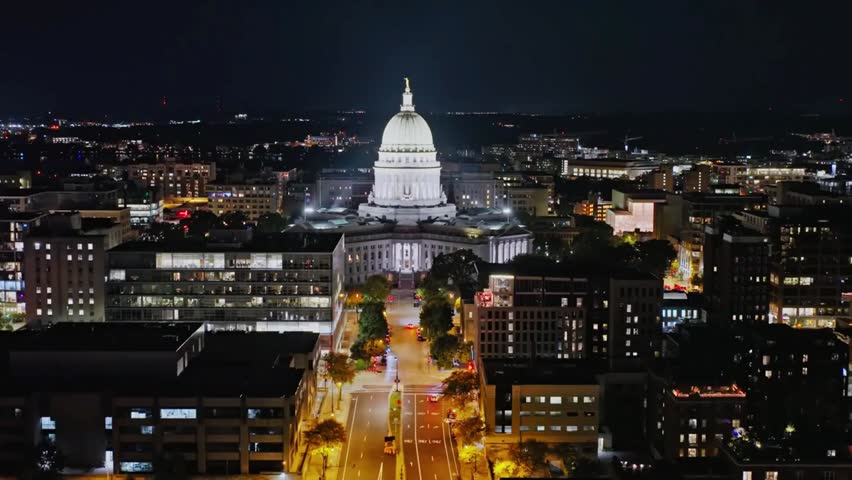 Aerial view of the Wisconsin State Capitol building illuminated at night in downtown Madison, highlighting historic architecture and city lights.
