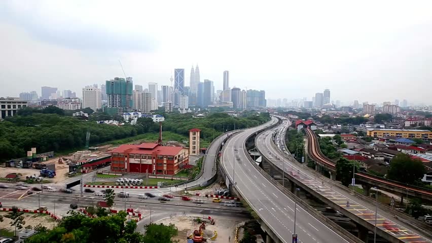 Kuala Lumpur skyline featuring highways and tall buildings under a cloudy sky, highlighting Malaysia’s urban architecture and bustling cityscape.