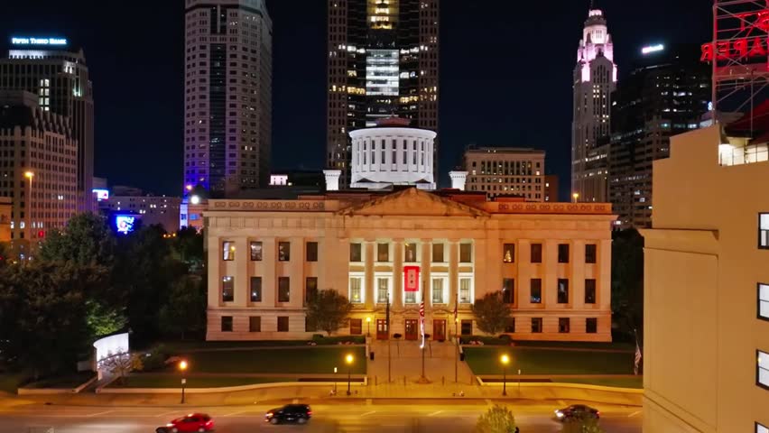 Ohio Statehouse glows at night with surrounding Columbus skyline lit up, highlighting the historic building and vibrant city lights in Ohio.