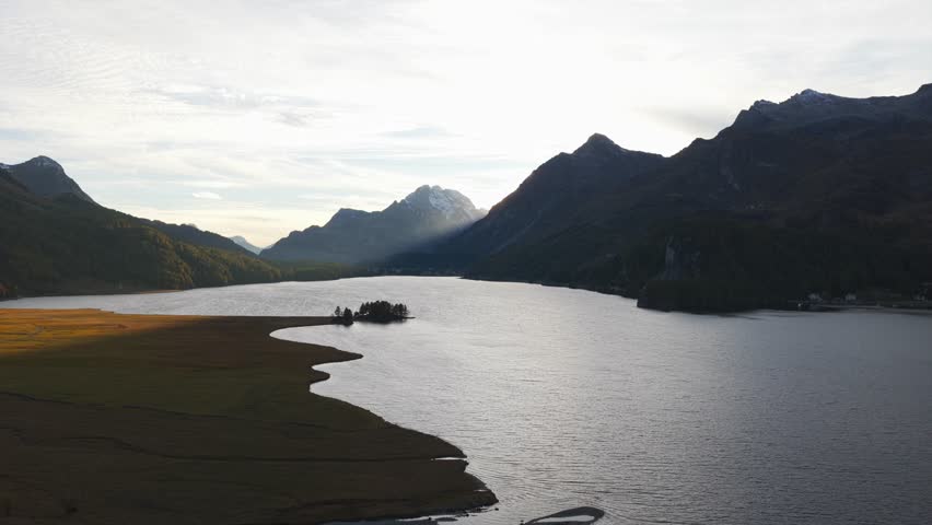 Drone view of mountains surrounding Lake Sils during sunrise in Graubünden, Switzerland. Aerial panoramic view, copy space