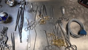 Close-up view of sterile surgical instruments neatly arranged on a stainless steel table in a hospital operating room. The image shows forceps, scissors, clamps, needle holders - Powered by Shutterstock - Get 15% off with code: PIKWIZARD15