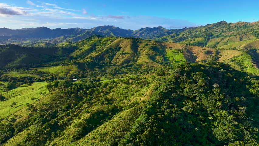 Green mountain landscape in summer. Lush green tropical forest covering mountain hills and a deep valley. Natural landscape of mountain peaks against the sky. The natural beauty of the landscape. Aerial flight footage.