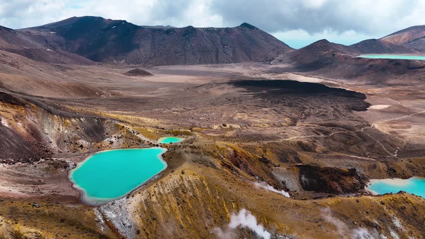 Blue crater lakes with fumeroles in rugged Tongariro Alpine Crossing, aerial