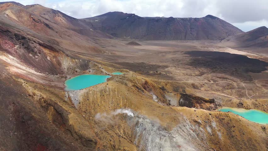 Cinematic drone view over turquoise crater lakes and volcanic terrain on the Tongariro Alpine Crossing, Tongariro National Park, North Island, New Zealand