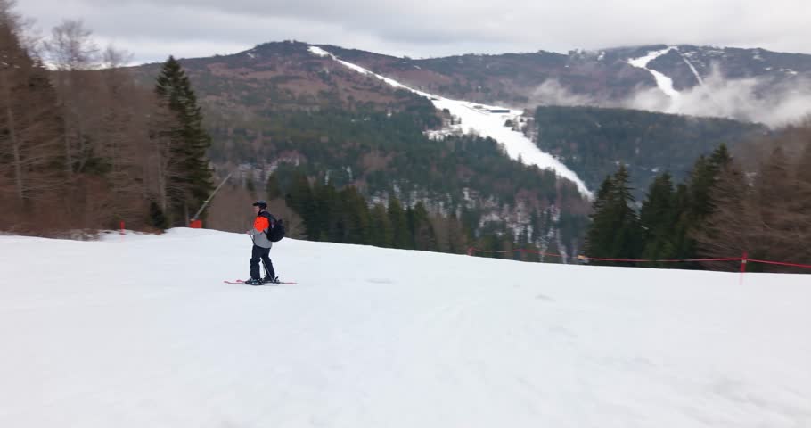 Dynamic aerial follow mode captures skier carving fast on pristine alpine piste in bright winter scenery