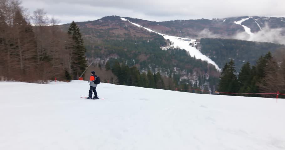 Dynamic aerial follow mode captures skier carving fast on pristine alpine piste in bright winter scenery