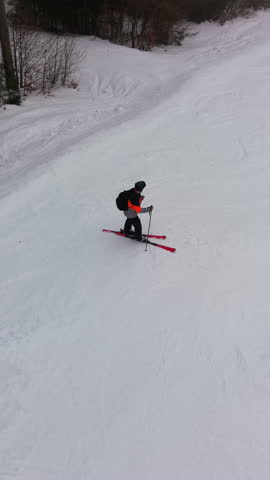 Dynamic aerial follow mode captures skier carving fast on pristine alpine piste in bright winter scenery