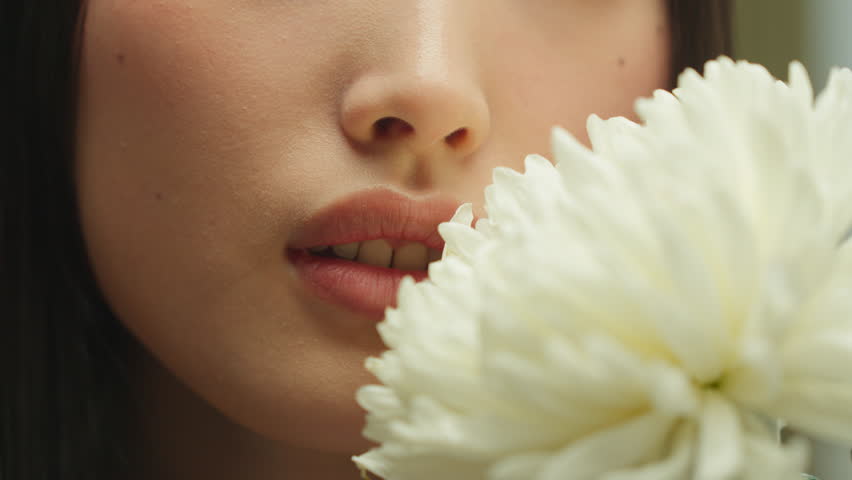 Closeup female plump seductive lips near white flower unknown Asian woman girl lady half face eco organic cosmetic product lip balm lipstick fragrance blossom perfume tenderness purity allergy concept