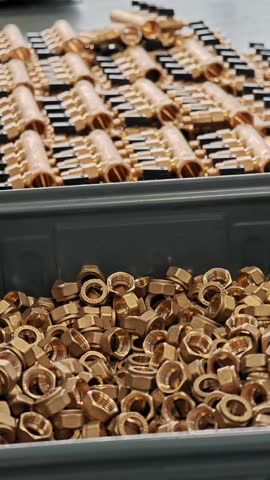 Vertical view of brass fittings in a bin with manifolds behind. Industrial plumbing production.