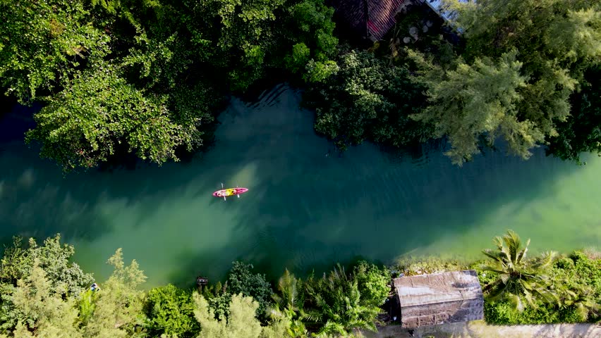 Kayakers glide effortlessly over the tranquil waters of Koh Chang, Thailand, surrounded by vibrant foliage and serene landscapes. A perfect escape into nature unfolds here.