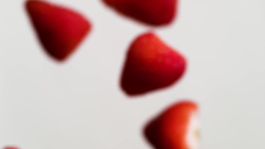 Slow-motion video of a fresh red strawberry falling into a glass of white milk. Featuring an aesthetic splash against a clean background. Perfect for health, breakfast, or dairy concepts.