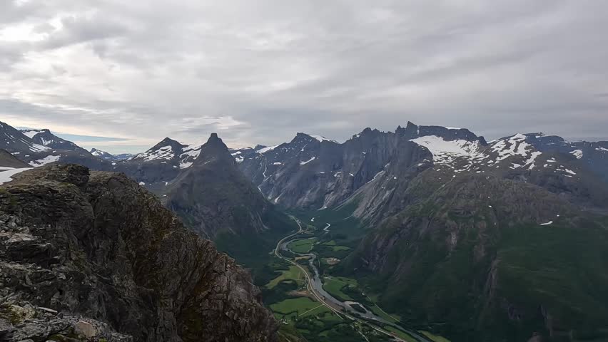 Elevated view from high ground toward mountain peaks and deep valleys. Classic Nordic landscape panorama under open sky.