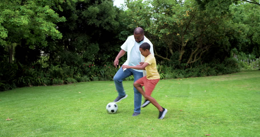 African American father and son playing soccer on lawn holding ball son stealing practicing control. Family, outdoor, backyard, grass, football, footwork, drills
