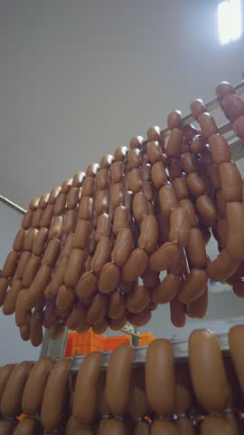 A row of hot dogs hanging on a rack. The hot dogs are brown and appear to be freshly made