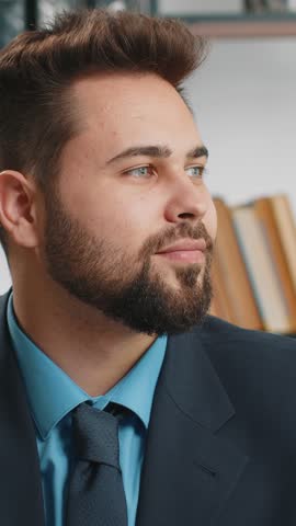 Portrait of happy smiling bearded Caucasian businessman at modern home office workplace desk look away turn head at camera. Male in formal suit. Handsome man remote distant online working on laptop