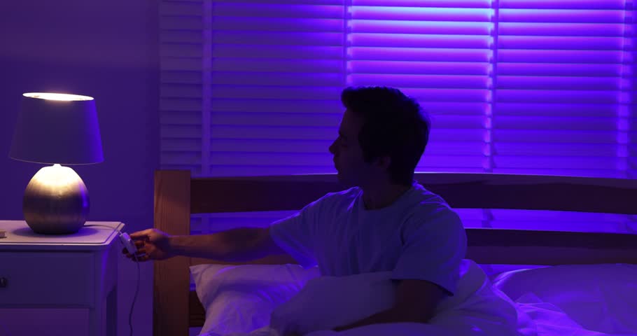 Man turning off night lamp and going to sleep in bed. Camera moving down