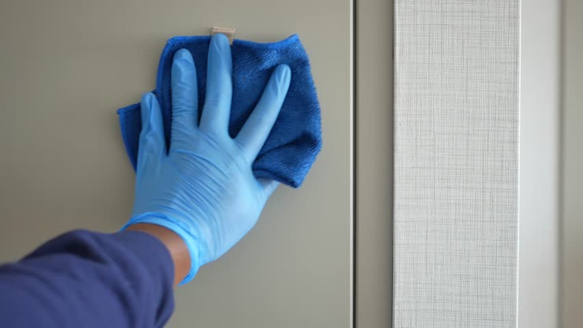 Person wearing blue gloves wipes surface with blue cloth, detailed shot