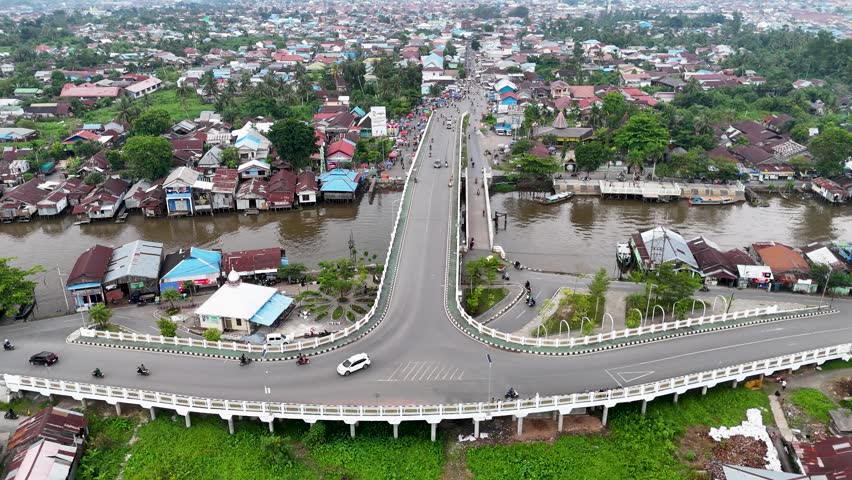 Explore Banjarmasin city from above as people move through the streets and across the river