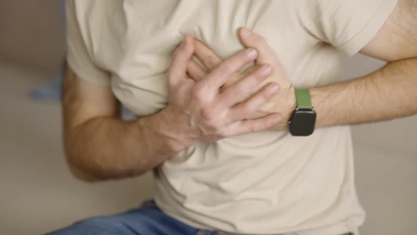 Patient Holding Hand Over Chest Pain Area Feeling Sharp Discomfort, Patient Suffering From Sudden Heart Attack Symptoms Or Chest Pain During Daily Life, Healthcare Emergency, Patient Touching Body To Show Chest Pain Location, Cardiovascular Health Issue, Medical Condition Awareness, Cardiology Distress Sign, Physical Ache Feeling, Diagnostic Symptom
