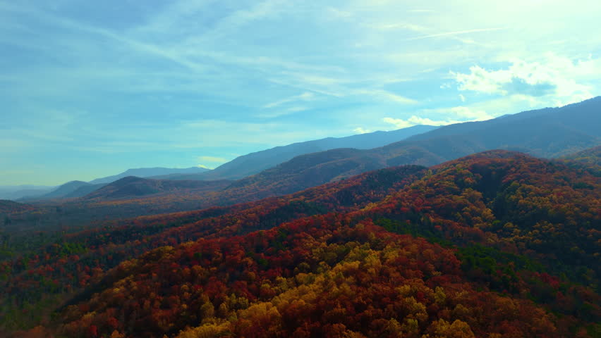 Drone Wide shot of the Great Smoky Mountains. Layers of distant blue mountains blend with the bright blue sky