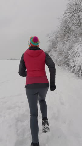 Slow motion following woman jogging in snow
