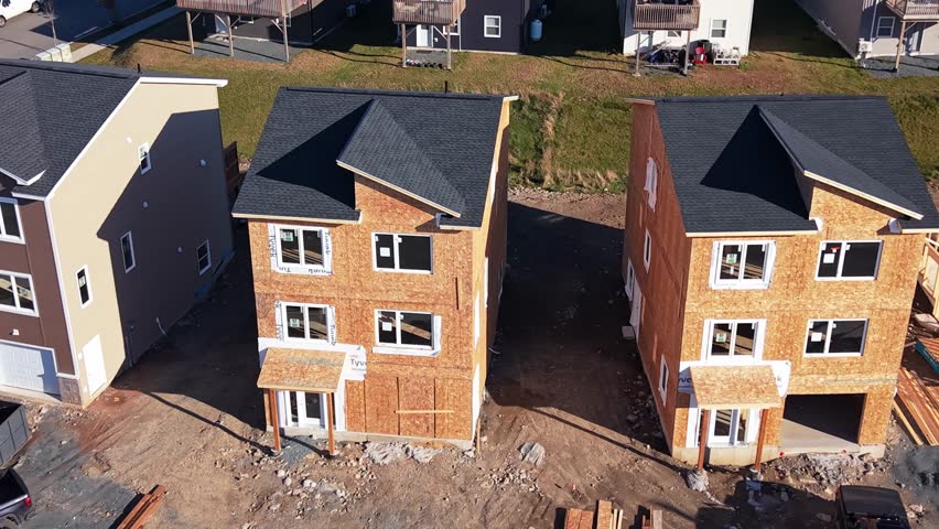 Cinematic aerial drone view at sunset: wooden frame structures of expensive modern houses under construction in Beechville suburb of Halifax. Nova Scotia Canada summer housing boom, golden hour 