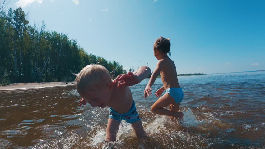Summer family fun. Kids run around on the summer beach and in the river