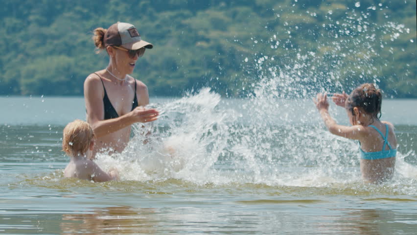 Family with kids has fun on the summer lake, enjoy the sunny weather and play with water