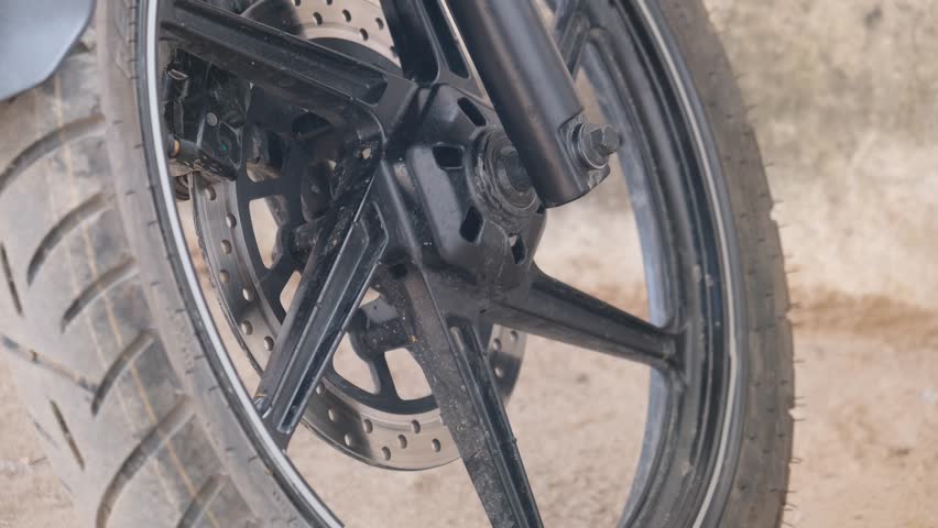 Close-up of a black motorcycle front wheel featuring a disc brake system.
Tags: motorcycle, wheel, disc brake, tire