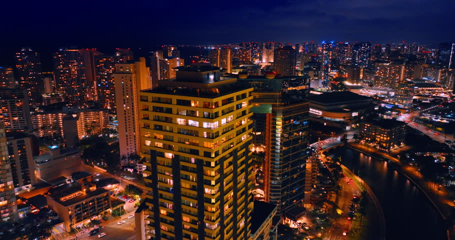 Dazzling high-rises of the vibrant city. Drone footage at the tops of the buildings at night. Honolulu, Hawaii, USA.