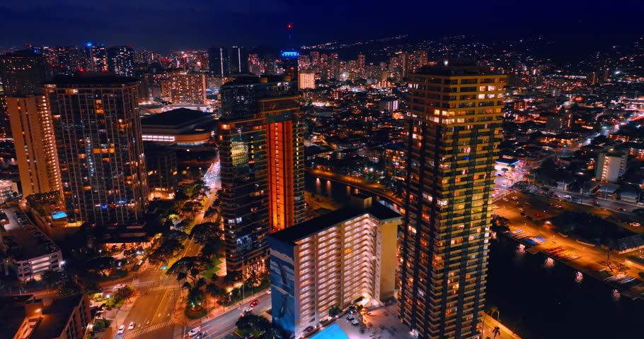 Lively traffic on the roads of night resort. Stunning illumination of modern Waikiki, Honolulu, Hawaii, USA. Aerial view.
