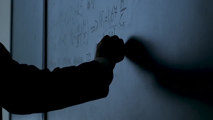 Close-up of a scientist writing physics formulas on a black chalkboard with chalk, illustrating science, education, and research concepts.