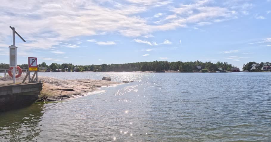 Ferry leaving floating concrete pontoon dock at Pirttisaari on a summer day with clouds in the sky, Finland, Europe.