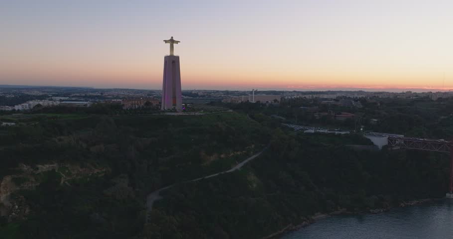 Cristo rei Jesus Christ statue in Lisbon, Portugal. Sunset, night, dusk, aerial drone shot