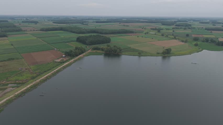 Aerial view of serene lake surrounded by lush green fields and trees