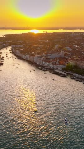Stunning aerial sunset over Venice grand canal with golden sunlight reflecting on water and moving boats